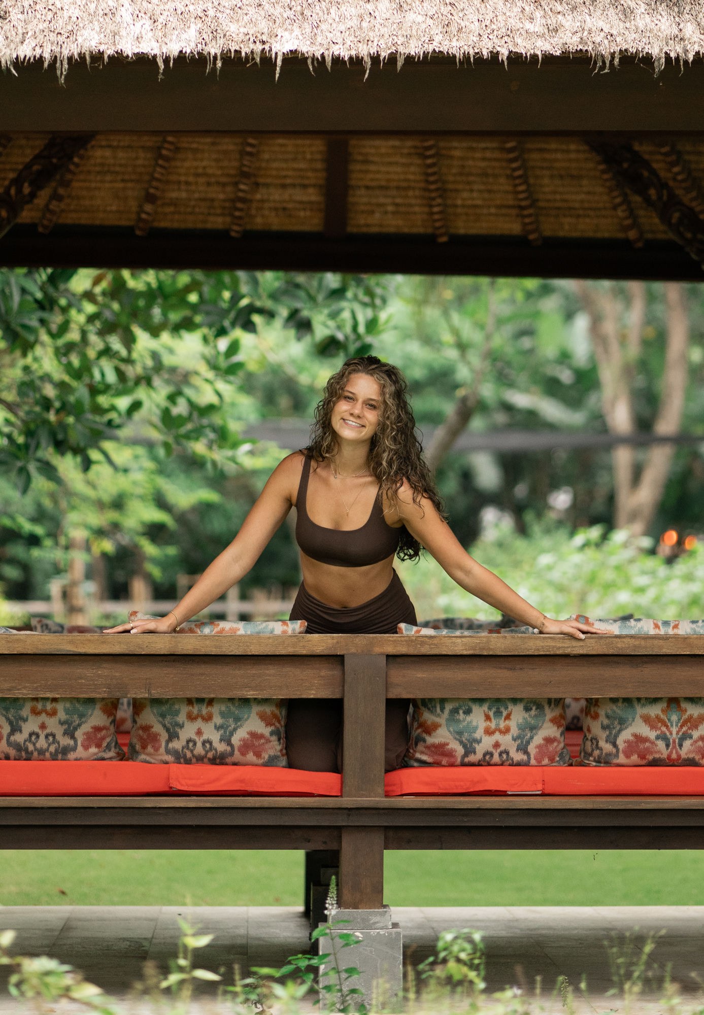 Josee standing in a thatched garden pavilion, hands resting on the railing